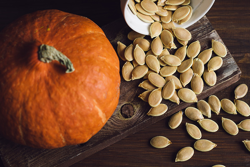 Bowl with dried pumpkin seeds and a pumpkin