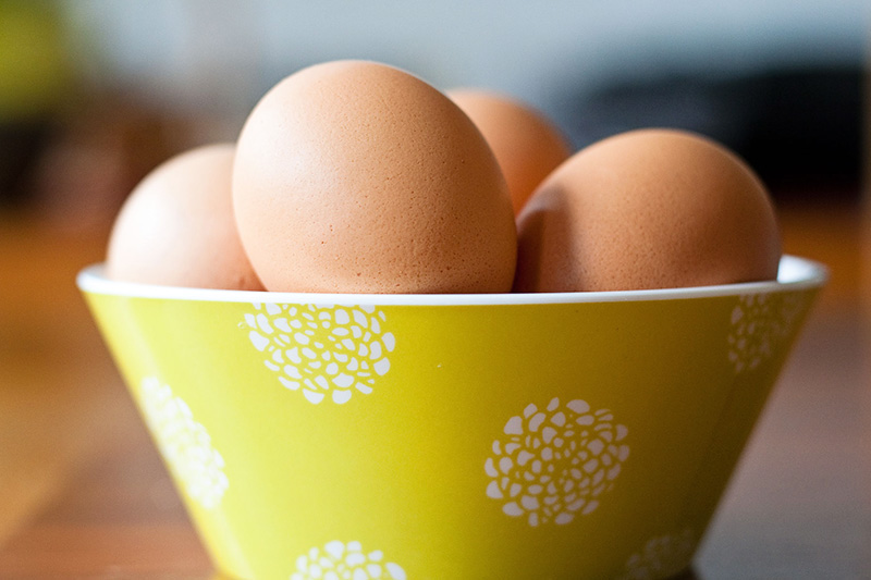 An olive green bowl of brown eggs