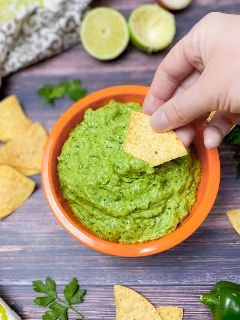 a bowl of guasacaca with tortilla chips for dipping