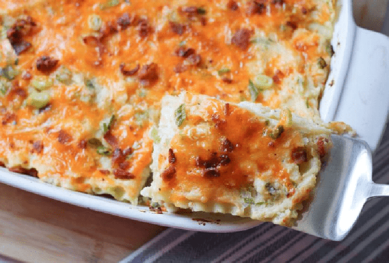 A scoop of pierogi lasagna casserole held over a baking dish