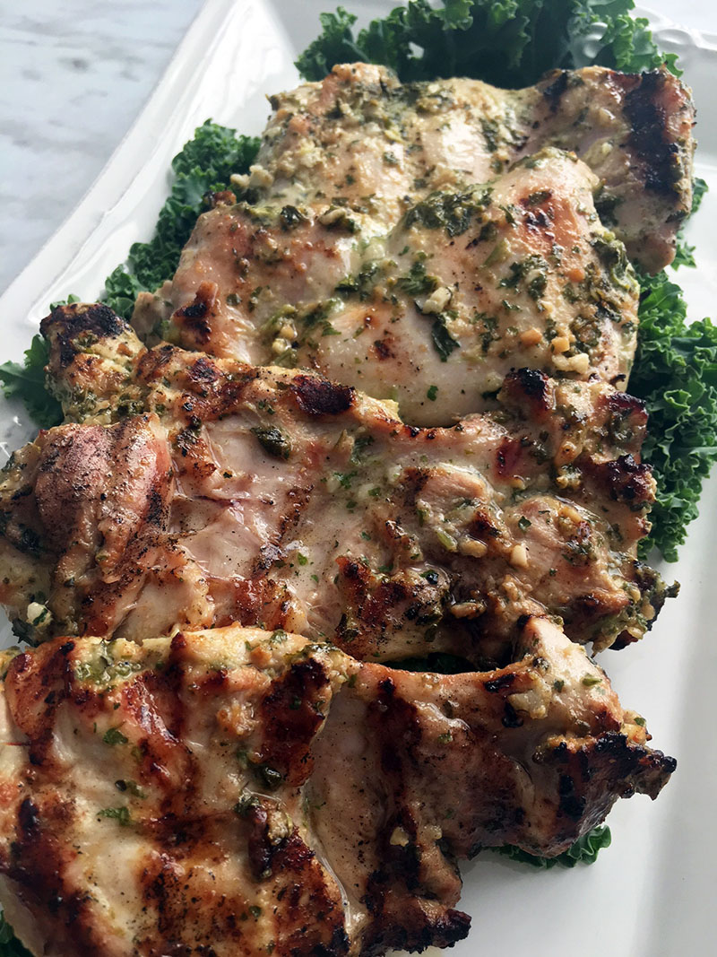 a serving platter of cilantro mint chicken on a bed of kale