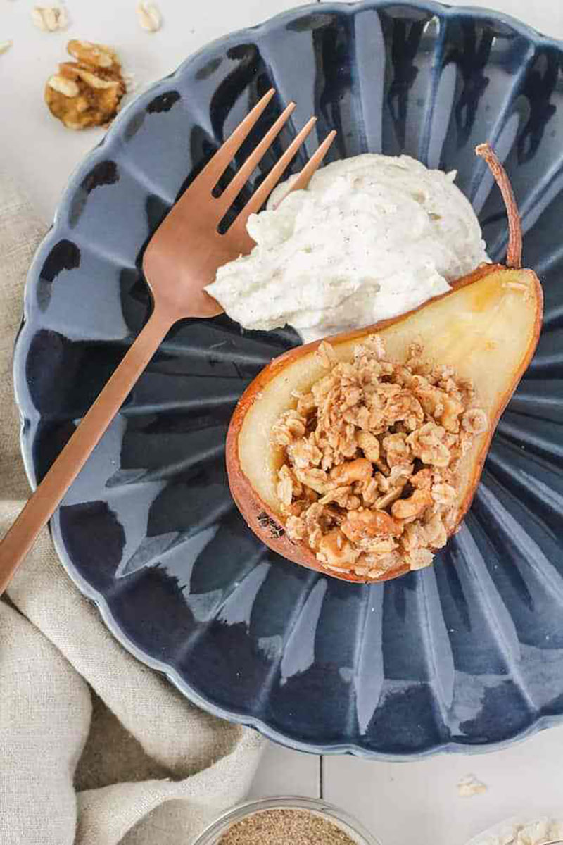 Half a baked pear with cardamom cream and granola topping