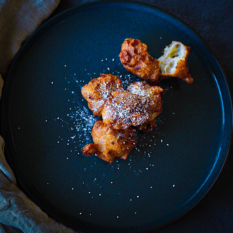 Fresh apple beignets on a blue ceramic plate