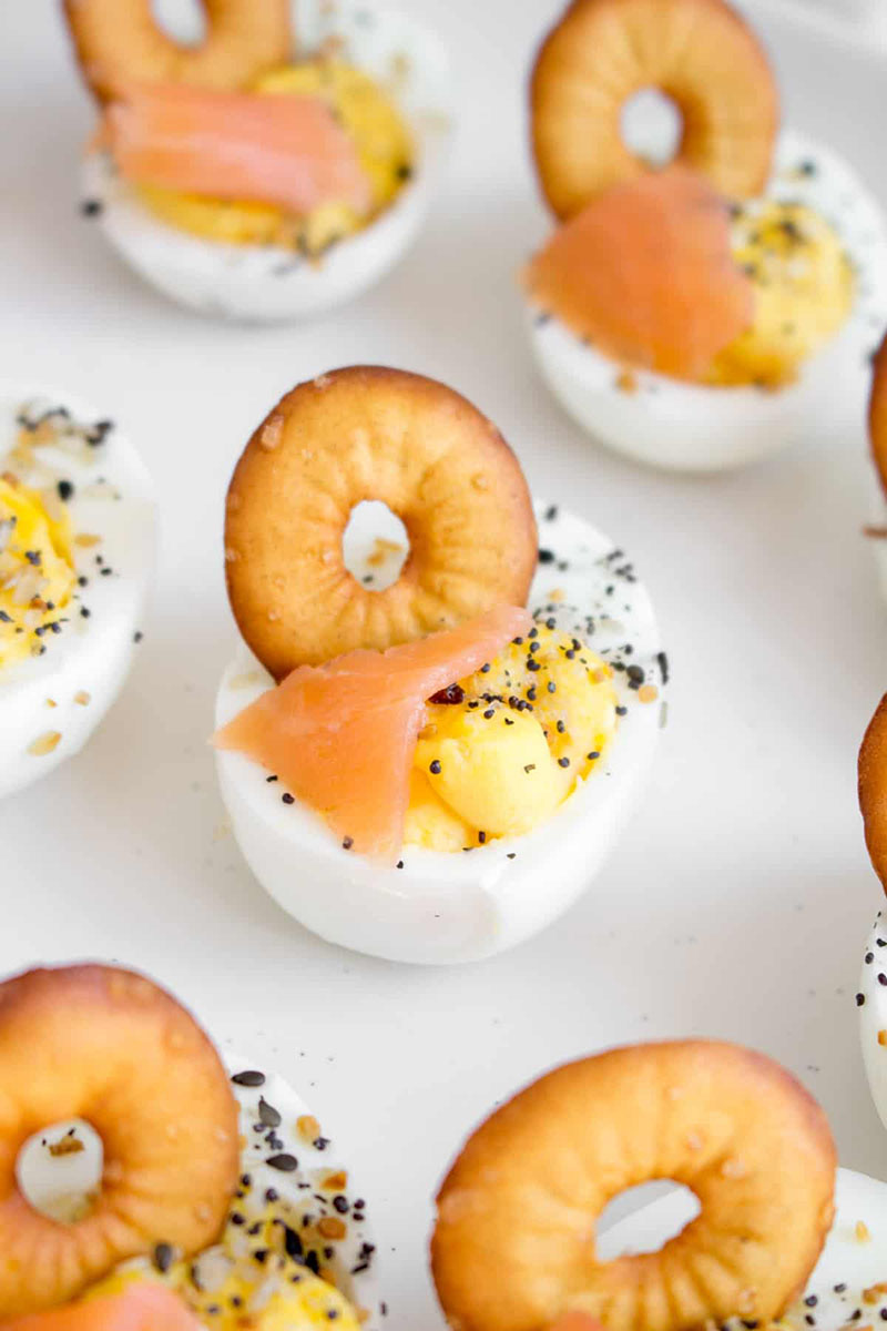A plate of deviled eggs with smoked salmon and bagel chips