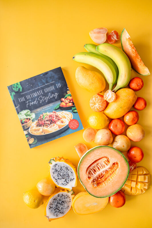 Food styling book with fresh fruits around it.