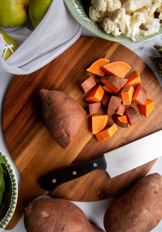 Diced sweet potato on cutting board with knife.