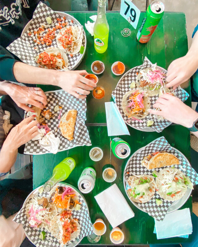 Table set up with food and people reaching out for food.