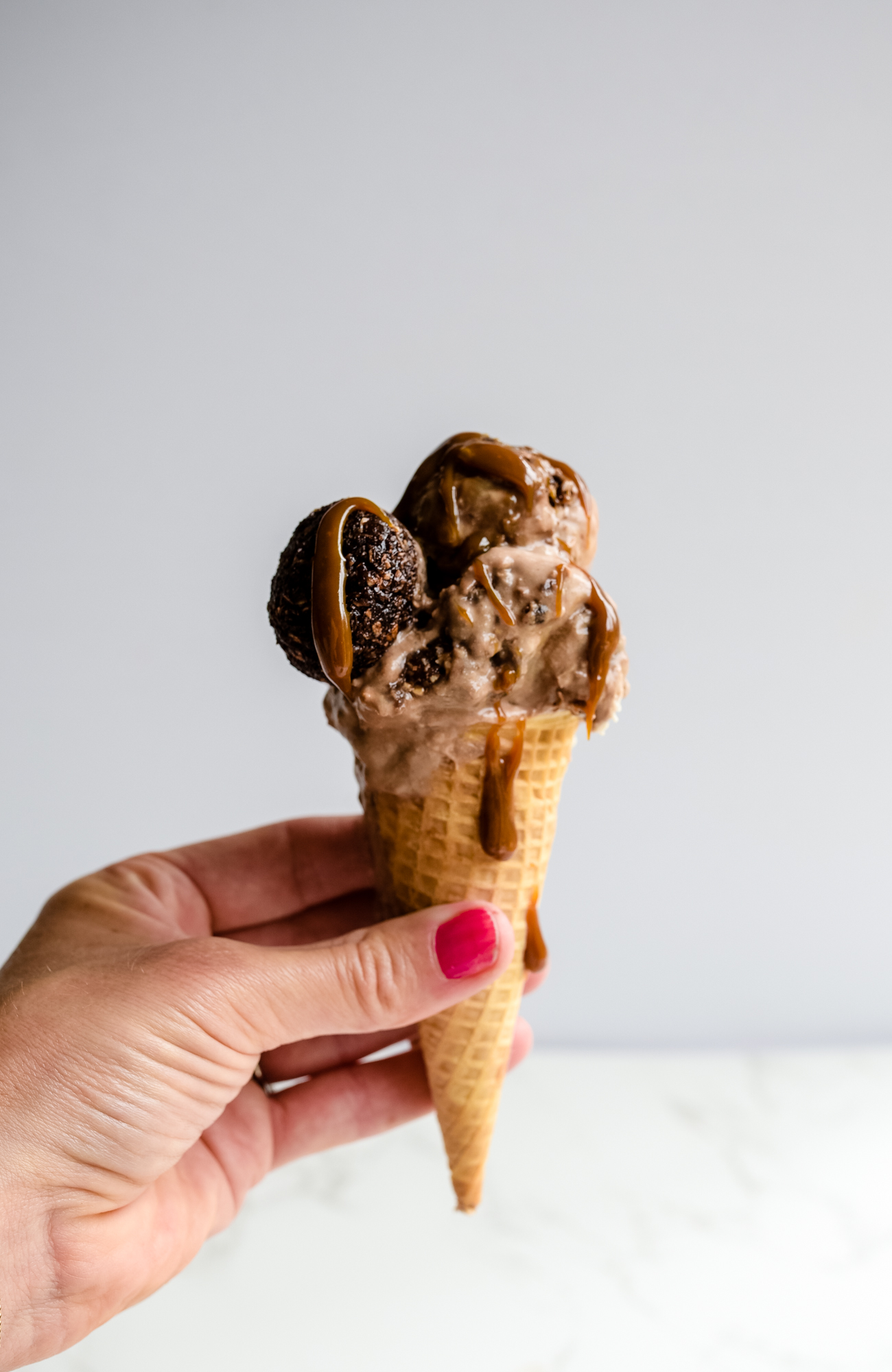 A hand holding waffle cone with ice cream.