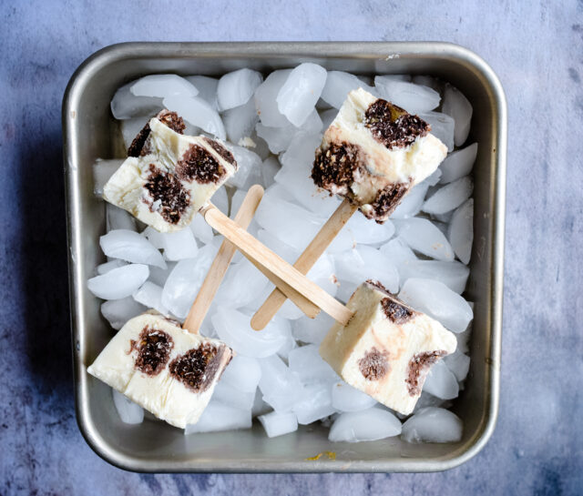 Hazelnut ic ecream popsicles on a tray with ice cubes.