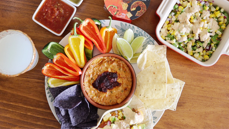 Queso dip with cheese served with chips and peppers.